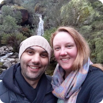 Harley and Tahlee standing in front of green trees and a waterfall smiling